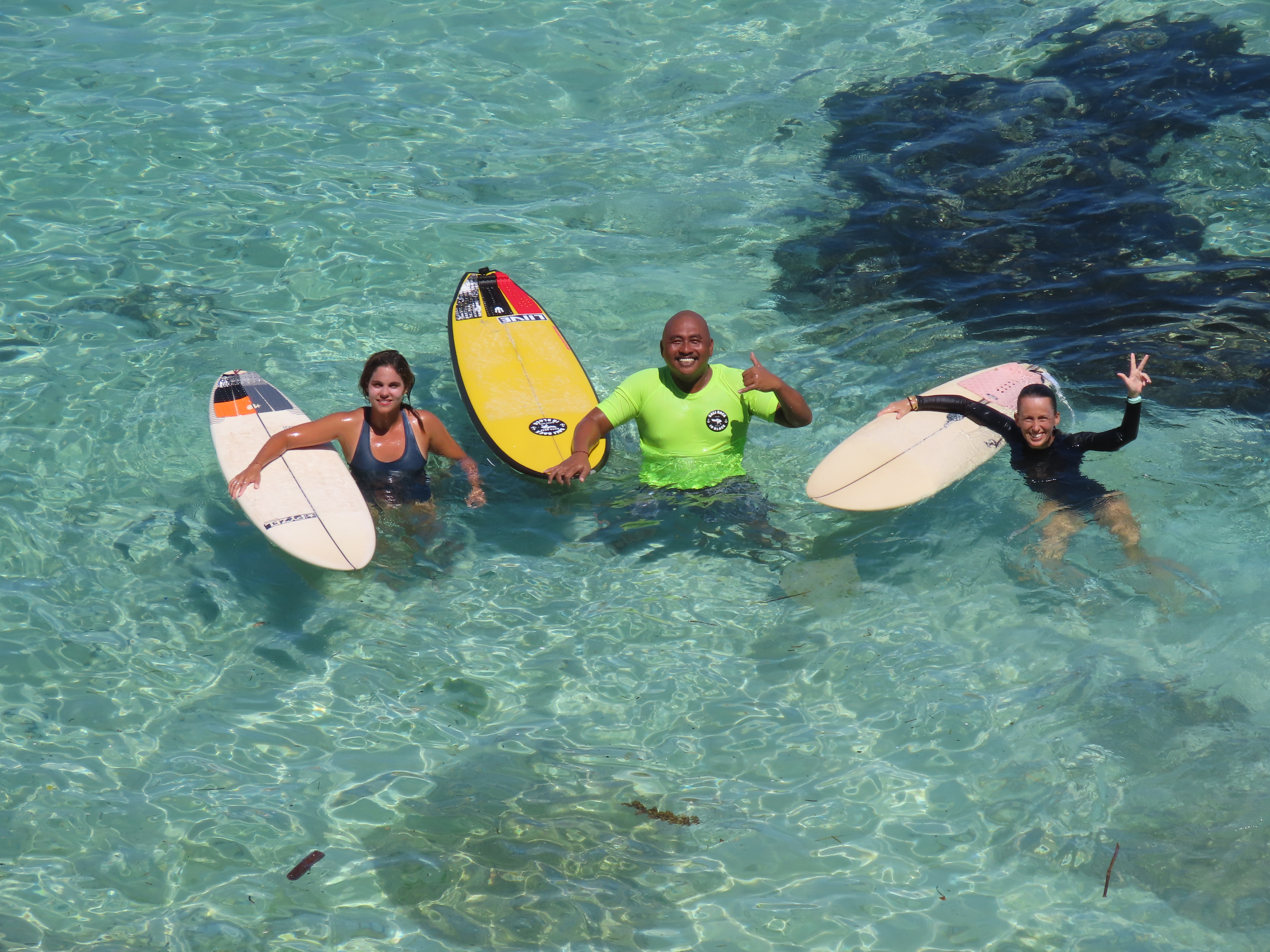 Surfers in crystal clear turquoise water at the reef in Bali