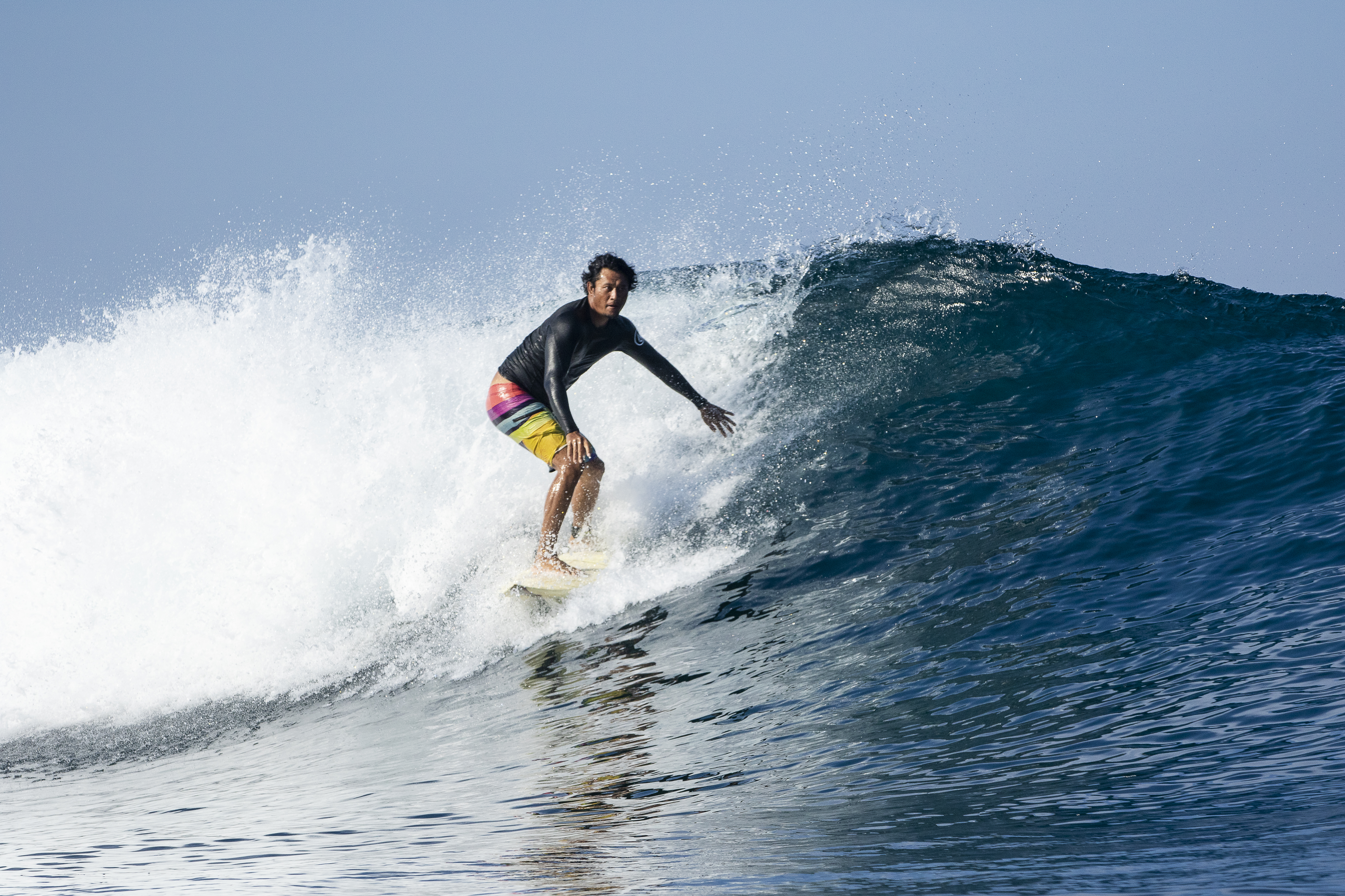 Surfer in rainbow shorts carving a wave