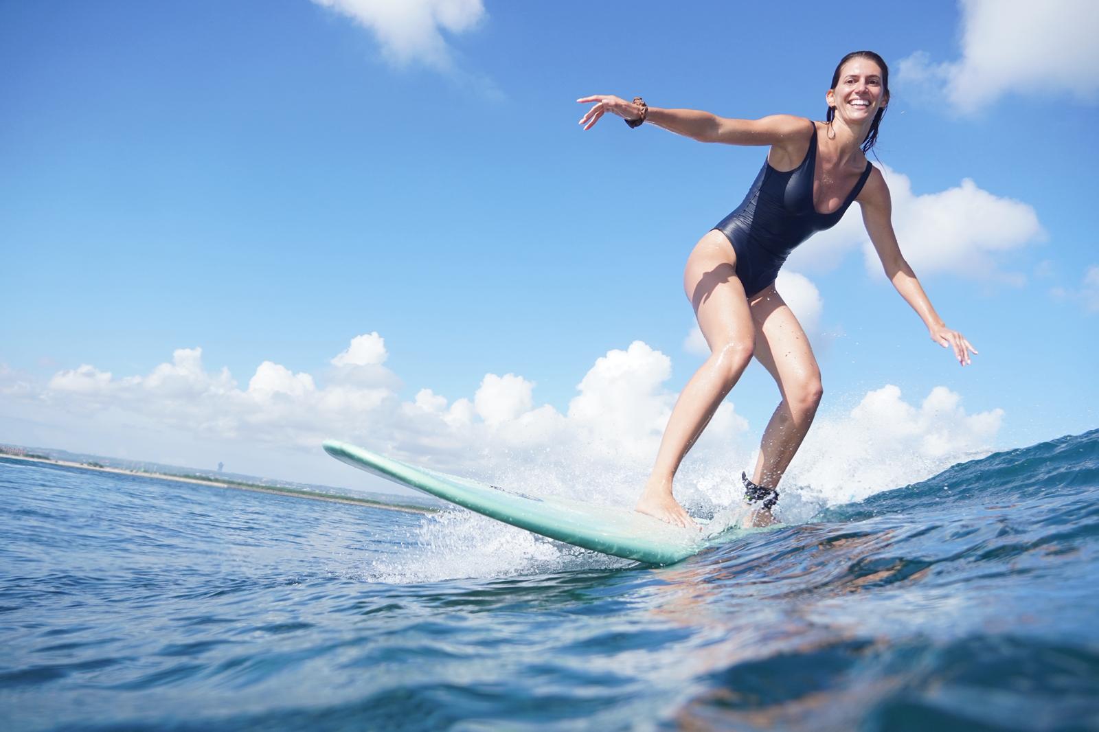 Surfer laughing while riding a longboard in Bali